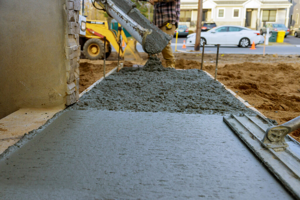 Construction worker in Washington IL pouring reinforced concrete cement for sidewalk in new residential home