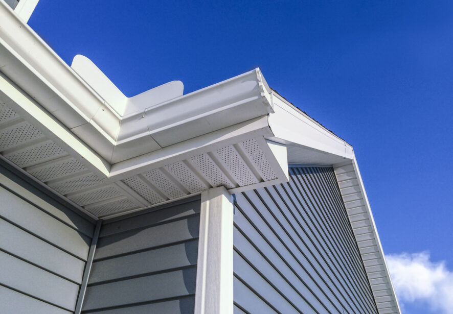 A low angle view of soffit, gutters, downspout and vinyl siding on a home completed by Central Illinois Construct, which is one of the top siding companies in Central Illinois